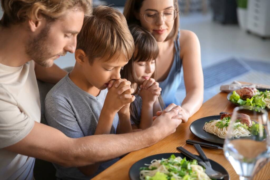 Christian values reflected in family prayer before a meal.