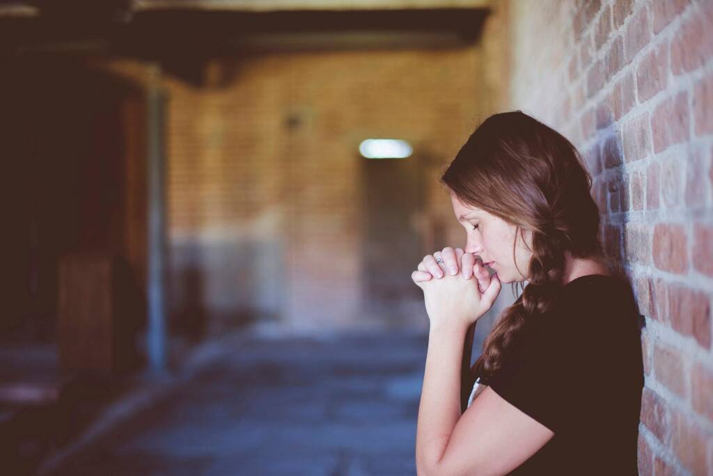 Young woman finding God, praying in private.
